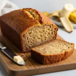 A perfectly moist loaf of banana bread made with 2 bananas, with one slice cut to show the tender interior crumb.