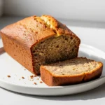 A moist loaf of banana bread made with no butter, with one slice cut to show the tender inside.