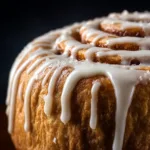 Sourdough cinnamon roll dough rolled into a log and being cut into individual rolls using dental floss for a clean cut.