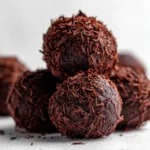 An extreme close-up macro shot of a rich dark chocolate raspberry truffle, showing the smooth texture of the ganache filling.