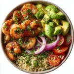 Shrimp and Avocado Power Bowl: The Ultimate Healthy Meal A close-up overhead view of the ingredients for a healthy shrimp bowl, including sliced avocado, cherry tomatoes, and seasoned shrimp.