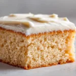 A close-up macro shot of a single moist vanilla cake square, showing the tender and fluffy crumb texture of the homemade cake.