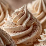 A close-up macro shot of perfectly piped peppermint meringue kisses before being baked, showing their glossy, stiff peaks.