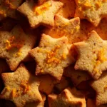 A close-up macro shot of star-shaped spiced shortbread cookies, showing their crumbly, buttery texture and golden-brown edges.