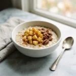 A warm bowl of apple cinnamon oatmeal topped with fresh apples and pecans.