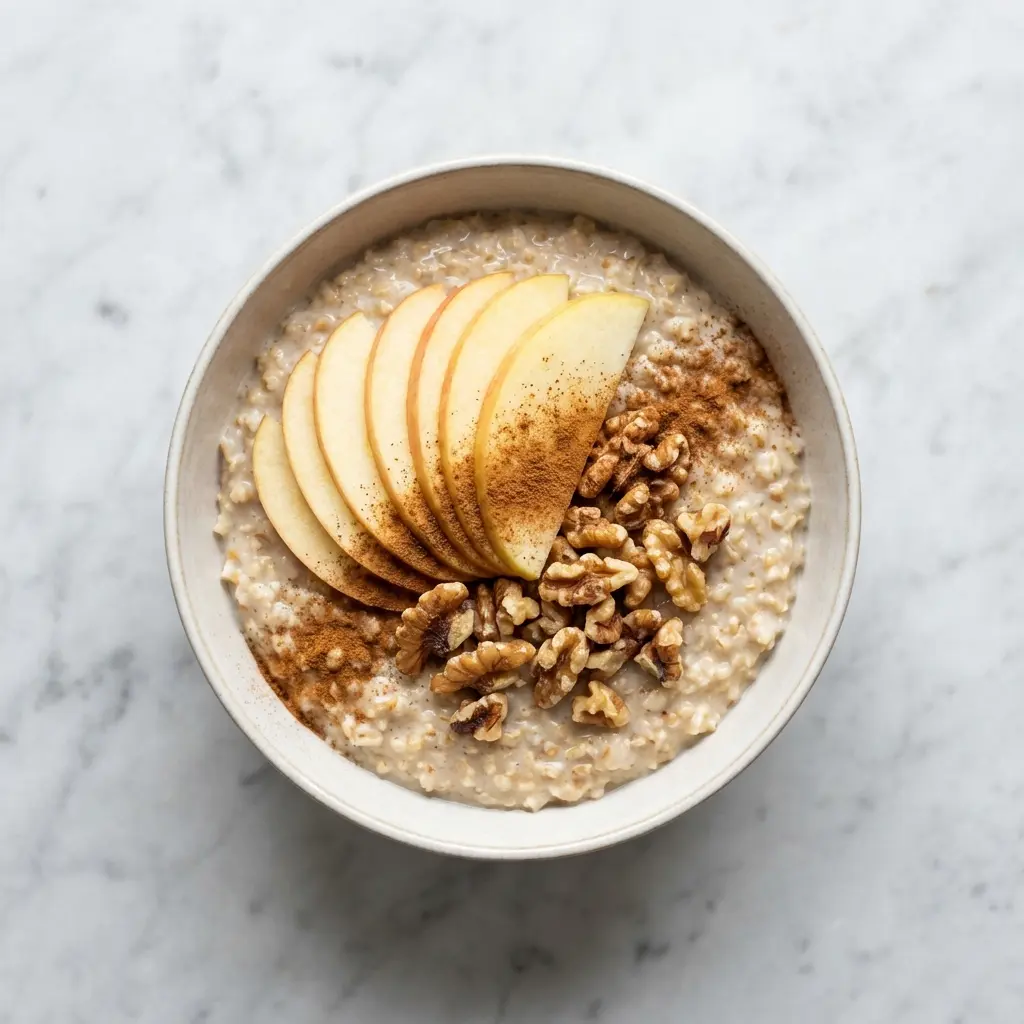 An overhead view of a bowl of apple cinnamon steel cut oats on a marble countertop.