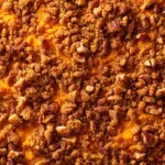 A top-down view of the baked sweet potato soufflé in its baking dish, highlighting the golden pecan crumble topping.