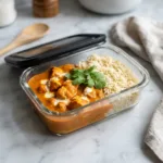 A glass meal prep container filled with delicious chicken tikka masala and basmati rice, ready for a week of healthy lunches.