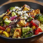 A close-up view of a healthy quinoa bowl with perfectly roasted chicken and colorful vegetables, showcasing the fresh textures of the dish.