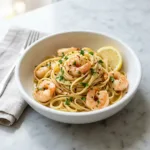 A close up shot of a bowl of one pan garlic butter shrimp pasta, garnished with fresh parsley.