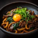 A close-up view of homemade yaki udon, highlighting the glossy sauce coating the thick, chewy udon noodles and crisp vegetables.