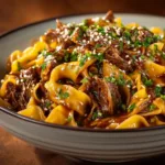 A close-up shot of Korean beef noodle soup, highlighting the glossy sauce coating the tender beef and noodles.