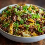 A close-up shot of a bowl of delicious Low-Carb Mongolian Ground Beef served over cauliflower rice and garnished with fresh green onions.