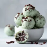 Mint Chocolate Chip Protein Balls (Easy, No-Bake Recipe) A stack of no-bake mint chocolate chip protein balls on a plate, showcasing their texture with mini chocolate chips visible.