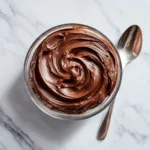 An overhead shot of a glass bowl filled with thick, rich chocolate filling before it has been whipped.