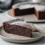 A single slice of rich, decadent chocolate torte on a white plate, showcasing its dense and fudgy texture.