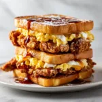 A close-up shot of the crispy fried chicken layered inside golden-brown French toast, creating the perfect sweet and savory sandwich.