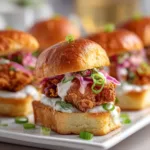 A close-up shot of a single homemade chicken slider, showcasing the craggy, crispy texture of the fried chicken and a toasted bun.