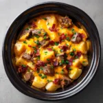 Tender diced russet potatoes and deeply browned seared steak bites coated in a creamy savory glaze inside a slow cooker.