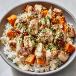 Overhead view of a savory Chicken and sweet potato bowl in a matte ceramic dish garnished with parsley and sesame seeds.