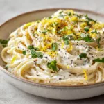Thick, velvety pale-white lemon ricotta sauce coating al dente spaghetti noodles.