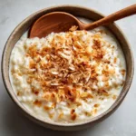 Thick, velvety white coconut milk pudding with visibly plump white rice grains suspended in the creamy sauce.