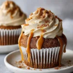 Detailed view of the spiced brown gingerbread cupcake base resting on a simple white ceramic plate, ready for frosting.