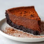 A close-up shot of a single slice of rich chocolate custard cake on a simple white ceramic dessert plate.