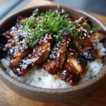Thick, juicy slices of pan-seared chicken thigh showing slight caramelization and charred edges, heavily coated in dark brown teriyaki sauce.