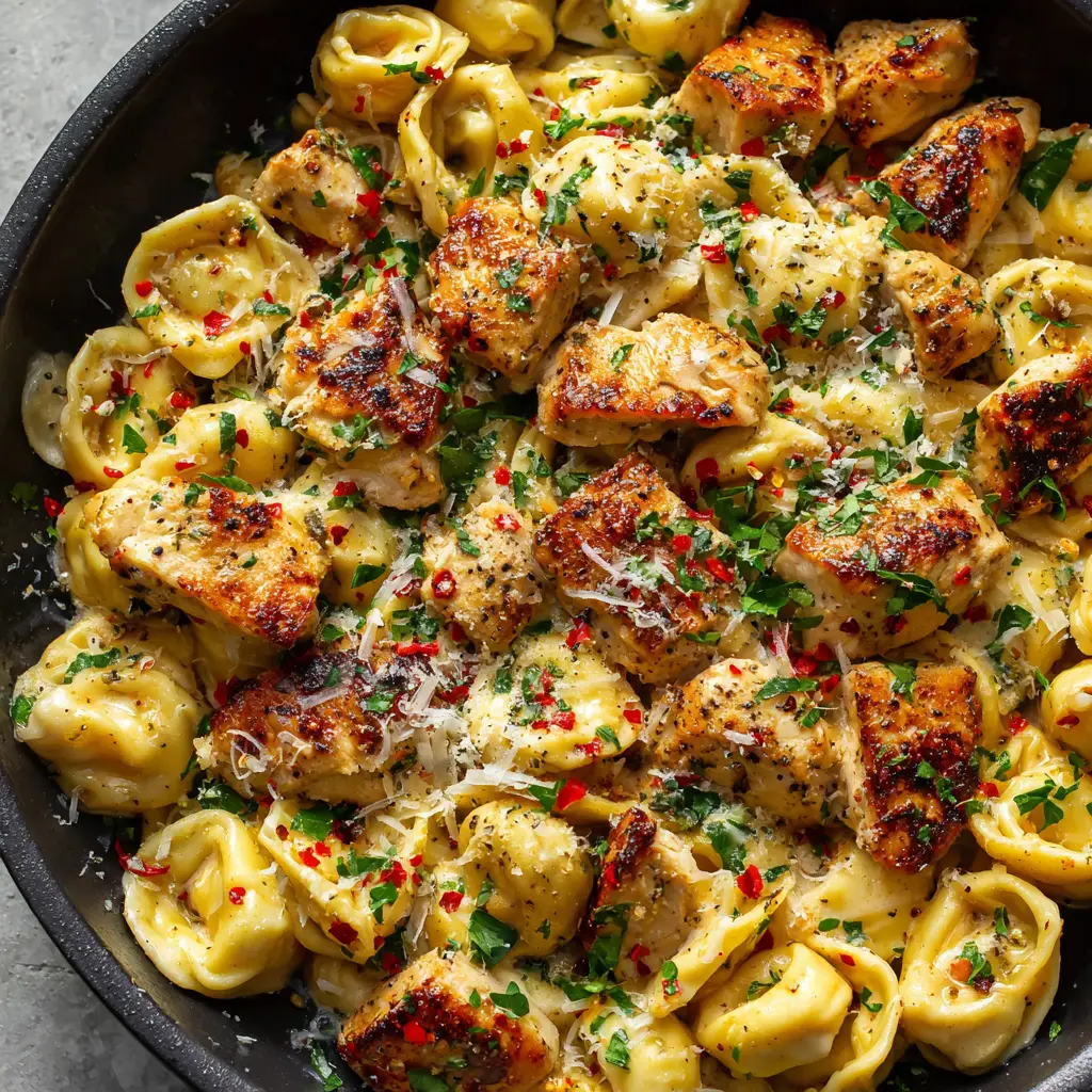 Freshly grated Parmesan melting into hot Garlic Butter Chicken Tortellini garnished with red pepper flakes and parsley.