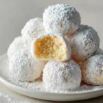 Close up shot showing a slightly broken baked snowball donut revealing a soft, golden-yellow baked crumb.