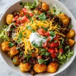 Crispy golden-brown roasted potato cubes dusted with red paprika seasoning forming the base of a taco bowl.