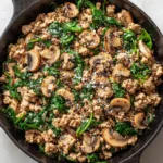 The Ultimate Turkey Spinach Mushroom Skillet Sizzling browned ground turkey and cremini mushrooms cooking in a seasoned black cast iron skillet with savory pan juices.