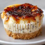 A close-up shot of a vanilla bean creme brulee cheesecake cupcake on a plain ceramic plate highlighting the dense filling.