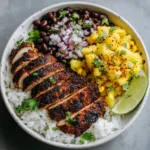 Close-up of grilled jerk chicken with deep char marks and a dark brown crust in a bowl.