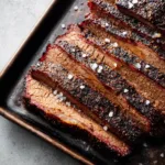 Top-down view of sliced Oven Baked Beef Brisket showing the glistening rendered fat and moist pink interior grain.