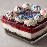 4th of July Dessert Lasagna: The Ultimate Patriotic No-Bake Layered Treat A square glass baking dish showcasing the multi-layered 4th of July Dessert Lasagna on a light surface.