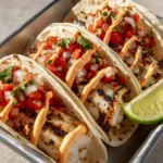 Close-up of Grilled Fish Tacos showing large flakes of charred white fish and bright red tomato toppings.