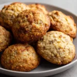 High-angle view of circular Chewy Banana Bread Cookies with a textured pale gold dough and visible cinnamon specks on a grey ceramic plate.
