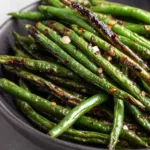 Macro close-up of Air Fryer Green Beans showing charred skins and glistening olive oil.
