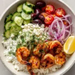 Greek Shrimp Bowl with Pan-Seared Paprika Shrimp and Lemon Vinaigrette Overhead smartphone photo of a Greek Shrimp Bowl with vibrant red shrimp, green cucumbers, and purple olives on a stone background.