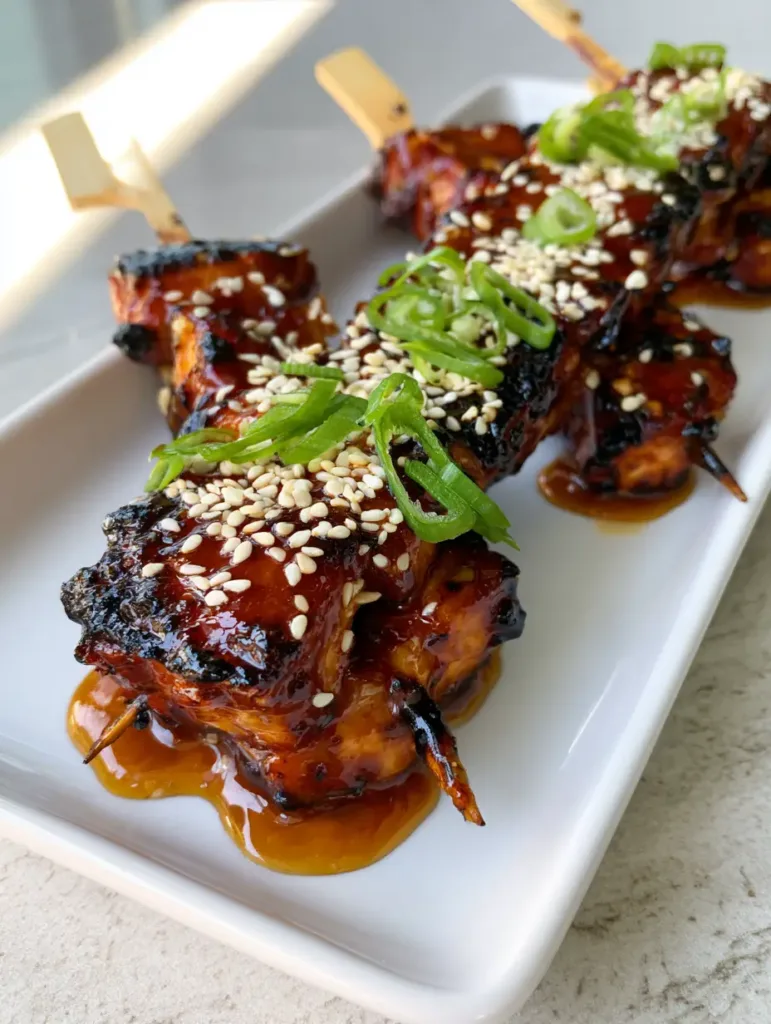 A close up of Honey Garlic Chicken Skewers showing charred edges and sesame seeds garnish.