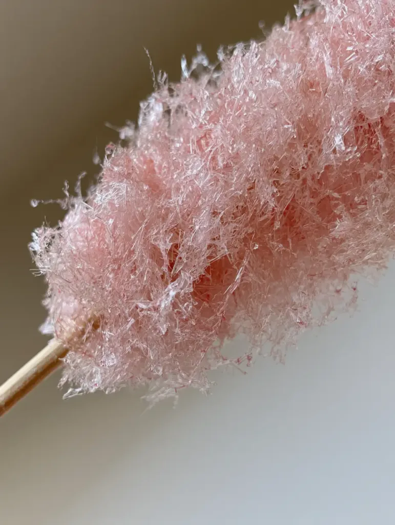 Fine delicate spun sugar threads held over a clean kitchen counter. (Homemade Cotton Candy Without a Machine)