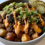 Close-up of a Smash Burger Bowl with melted cheddar and creamy orange special sauce over charred beef.