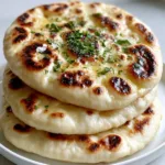 Close-up of Gluten-Free Vegan Naan showing dark brown leopard spotting and melted vegan butter.