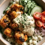 A smartphone photo of a round ceramic bowl containing charred cauliflower shawarma, quinoa, and fresh vegetables drizzled with tahini sauce.
