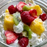 High-angle smartphone photo of Hawaiian Cheesecake Salad in a clear glass bowl on a light-toned countertop.