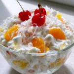 Better Than Sex Fruit Salad: The Creamiest 5-Ingredient Dessert Recipe Eye-level close up of Better Than Sex Fruit Salad showing the thick white whipped cream base and mandarin segments. (Better Than Sex Fruit Salad)