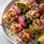 Greek Marinated Chicken Kabobs with Charred Peppers and Onions Eye-level shot of Greek Marinated Chicken Kabobs with charred onions and green peppers showing dark grill marks.