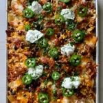 Rectangular silver baking sheet overflowing with loaded nachos on a light wooden table. (Vacation Meal Ideas)